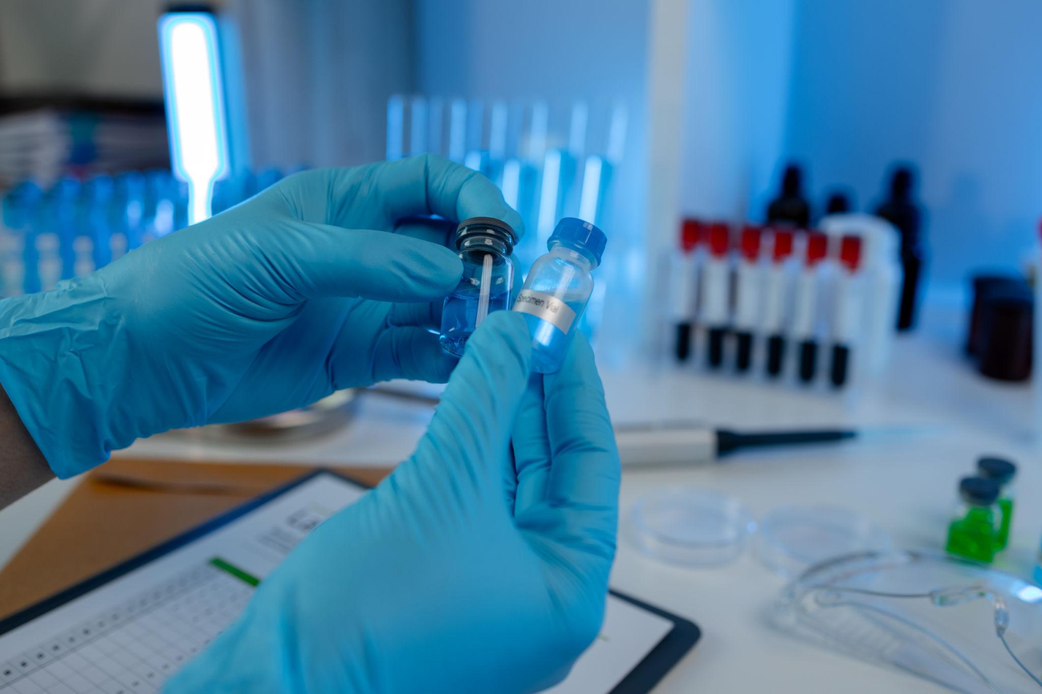 Laboratory researcher holding a vial with protective gloves